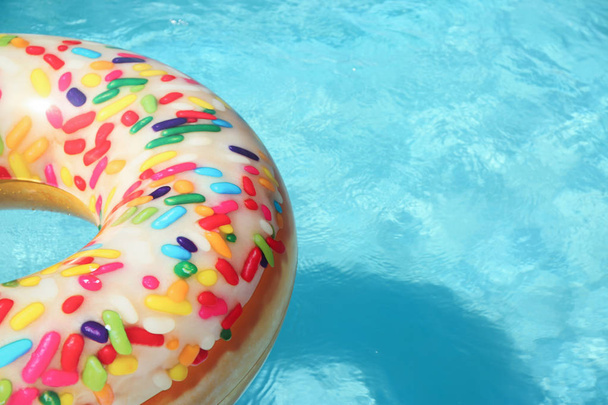 Bright inflatable doughnut ring floating in swimming pool on sunny day. Space for text - Fotografie, Obrázek