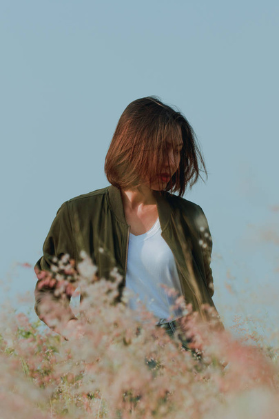 Женщина, стоящая на травяном поле с качающимися волосами
 - Фото, изображение