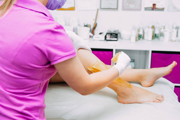 Removing unnecessary hair on the legs. sugaring in a beauty salon. Depilatory - Фото, зображення