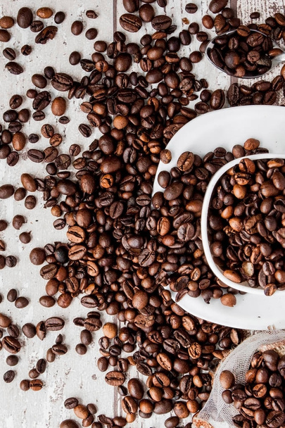 Black coffee in white cup and coffee beans on light wooden background. Top view, space for text - Fotó, kép