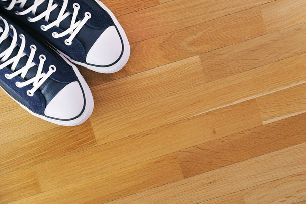 Blue sports sneakers on the background of a wooden floor. View from above. - Photo, Image