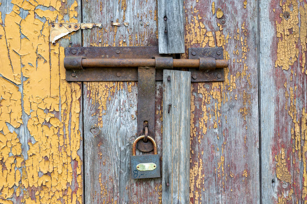 The old man wipes from a padlock in the door of the farm buildin - 写真・画像