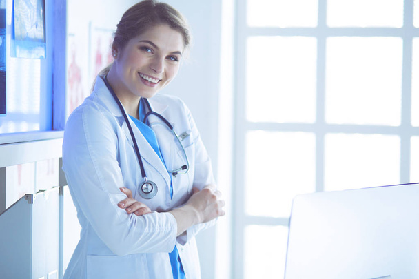 Młoda kobieta medyk w białym mundurze stojąca w gabinecie kliniki - Zdjęcie, obraz