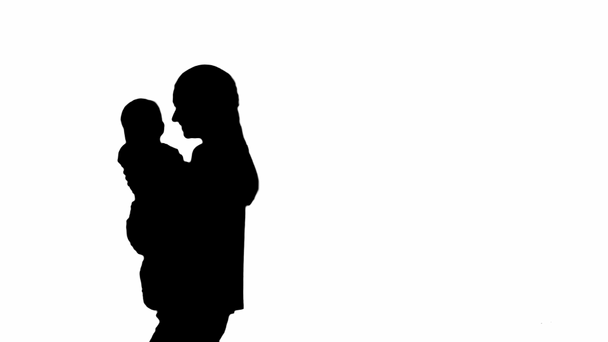 Silhouette Joven madre sosteniendo a su bebé en las manos y caminando
. - Metraje, vídeo