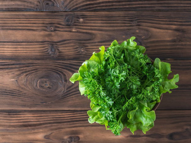 Lettuce and parsley in a bowl on a wooden table with a fork. Flat lay. - Photo, Image