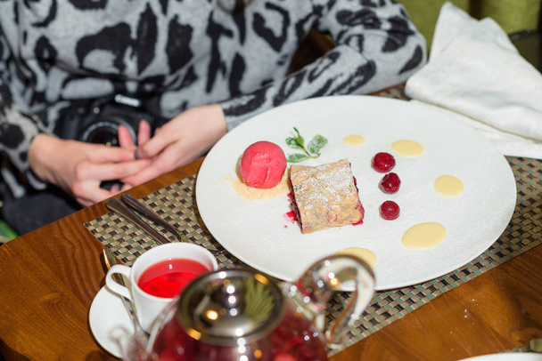 Cherry strudel on a white plate. Sweet dessert in the restaurant. Christmas tea with cake - Foto, afbeelding