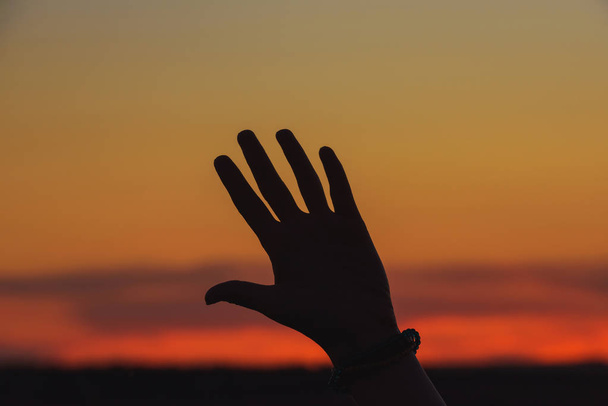 Dívčí ruka proti oranžovu západu slunce. Rekreace v Kazachstánu. Oranžový západ slunce na obloze. - Fotografie, Obrázek