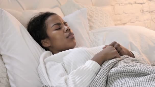 ベッドで寝ている間に咳をする病気の若いアフリカの女性 - 映像、動画