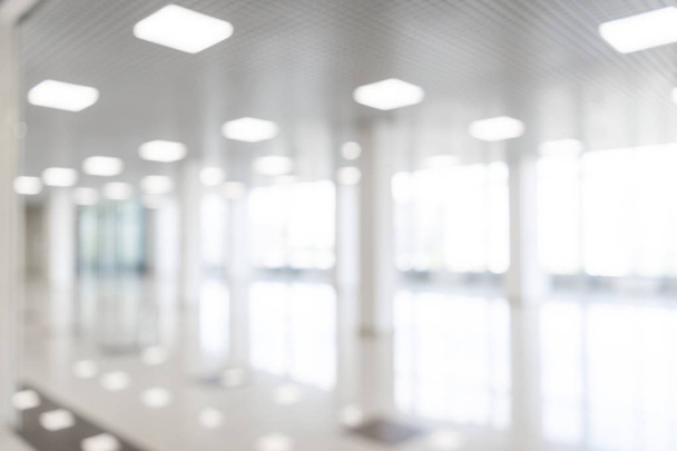 Blurred defocused bokeh background of exhibition hall or convention center hallway. Business trade show modern white interior architecture. Abstract blur modern business office background - Zdjęcie, obraz