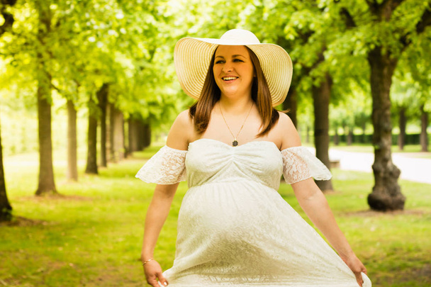 Mujer embarazada feliz posando sobre fondo verde natural
 - Foto, imagen