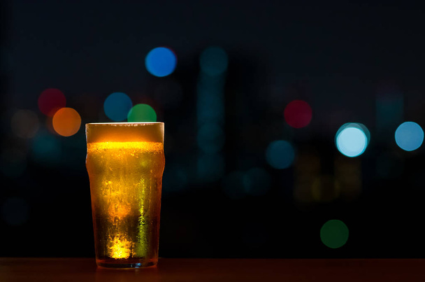 Un vaso de cerveza con su espuma pone en la mesa de madera de la barra
  - Foto, imagen