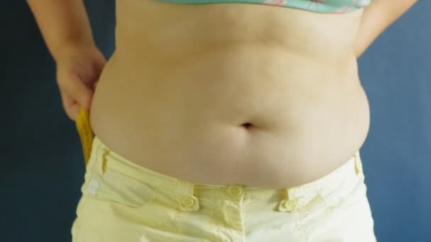 Gruba kobieta brzuch zbliżenie na niebieskim tle - Materiał filmowy, wideo