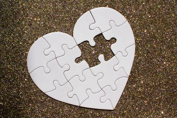 Bílé srdce tvarované puzzle na zlatém lesklém pozadí.  - Fotografie, Obrázek