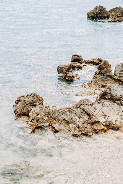  Stone walls and rocky shore. Rocks in the Bay of Budva, Montenegro. - Foto, afbeelding