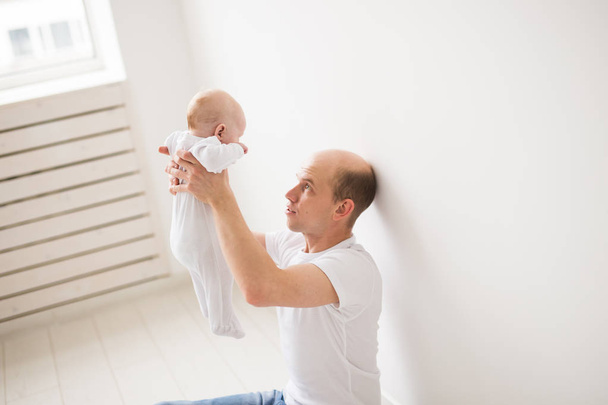 Дети, семья и отцовство концепция - счастливый лысый отец держа дочку на белом фоне комнаты
 - Фото, изображение