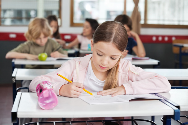 Schoolgirl Drawing In Book At Classroom - Fotó, kép