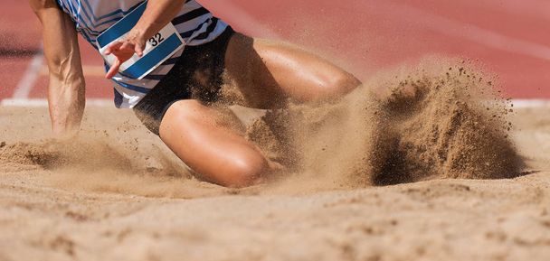 Naisurheilija pituushyppy lasku hiekka spray
 - Valokuva, kuva