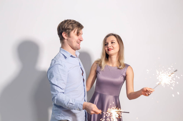 Fél, szórakoztató és ünnepek koncepció - fiatal pár boldog csillagszórók fehér háttér - Fotó, kép
