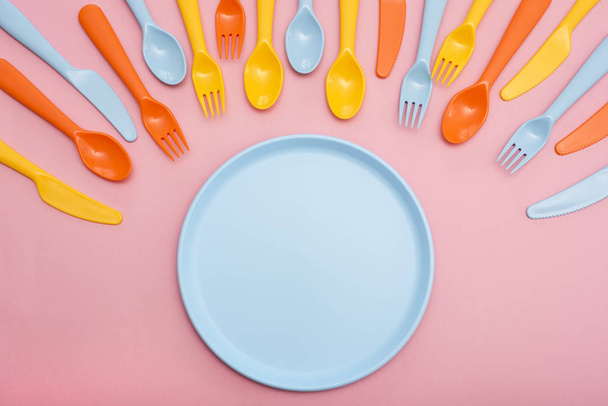 Vaisselle colorée : cuillère, couteau, fourchette et plaque de couleur bleue sur fond rose
. - Photo, image