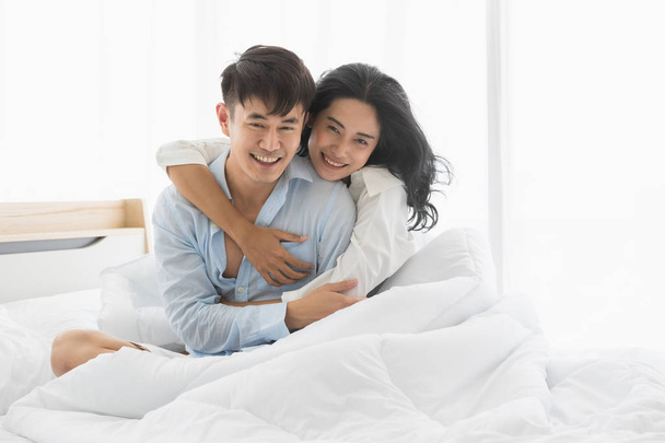 Paar sitzt auf dem Bett, sie umarmen sich aus Liebe - Foto, Bild