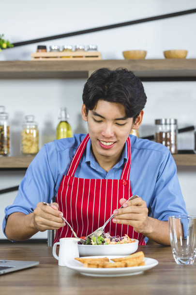 Asyalı adam mutfakta salata yiyor.. - Fotoğraf, Görsel