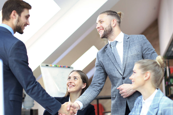 Business partners handshaking over business objects on workplace. - Foto, immagini