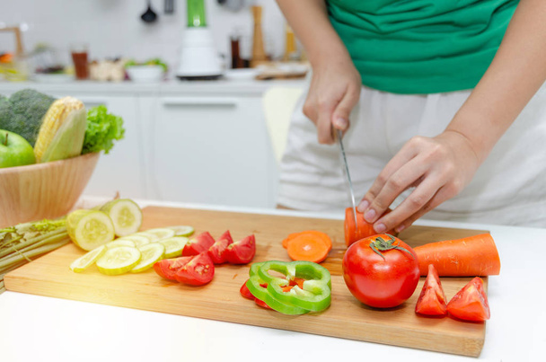 Diet. young pretty woman in green shirt cutting cooking and knife preparing fresh vegetables salad for good healthy in kitchen at home, healthy lifestyle, cooking, healthy food and dieting concept - Фото, зображення