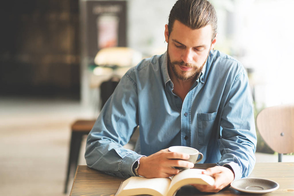 Male freelancer in blue shirt reading a book. - Fotoğraf, Görsel