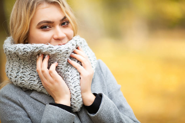 Cold and flu. Young woman in a gray coat walking in the autumn park and warms frozen hand - Foto, imagen