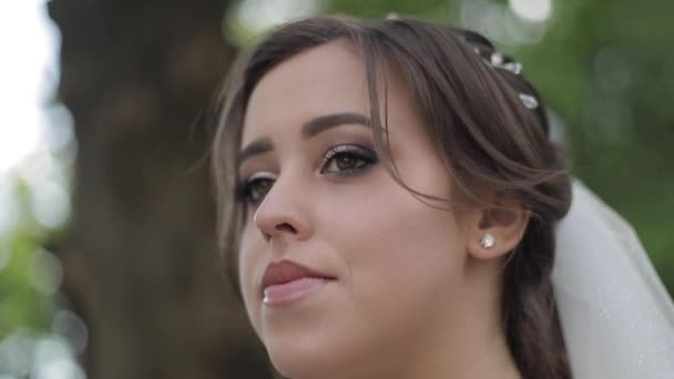 Charming bride in gorgeous wedding dress hold bouquet and stand in front of blooming trees - Footage, Video