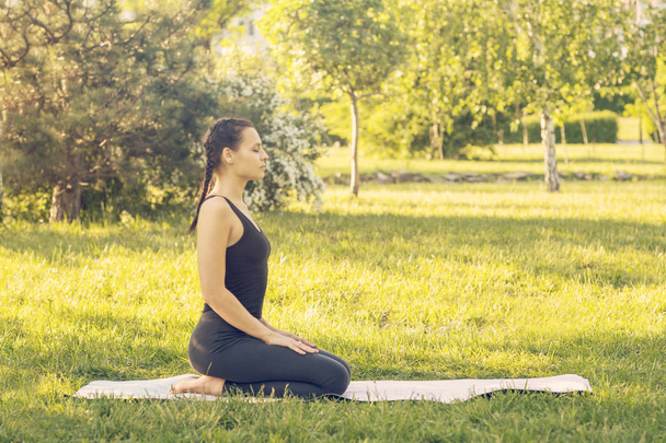 Young Caucasian woman doing yoga in the Park. Sitting meditating - Foto, Imagem