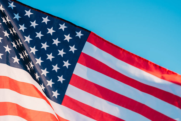 Αμερικάνικη σημαία σε γαλάζιο ουρανό, κοντά. Σύμβολο της ημέρας ανεξαρτησίας τέταρτη Ιουλίου στις ΗΠΑ - Φωτογραφία, εικόνα