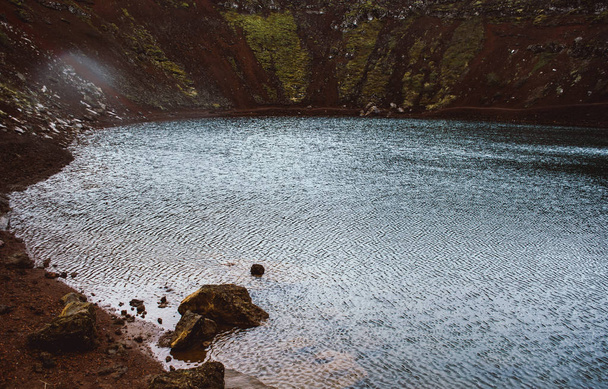 南アイスランドの火山クレーター内に位置するケリド湖の濃い青い水。湖面全体の風による雨滴と小波 - 写真・画像