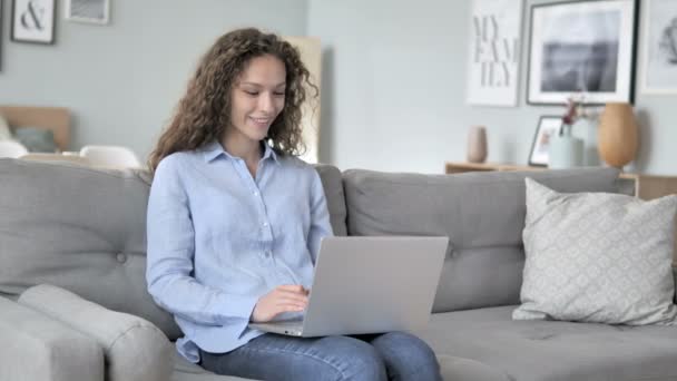 Online chat βίντεο για το laptop από σγουρά μαλλιά γυναίκα κάθεται στο δημιουργικό χώρο εργασίας - Πλάνα, βίντεο