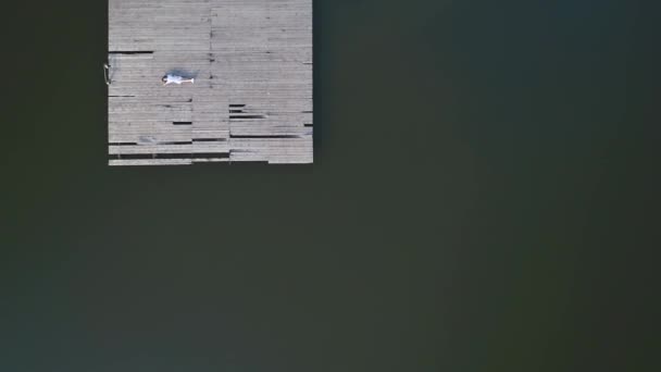 Vlieg over de drone-weergave van een geweldig meisje dat op de pier legt en blij is met de zon. 4k. - Video