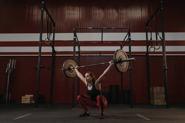 Silna kobieta CrossFit robi przysiady z narzutami Brzana. Fit yo - Zdjęcie, obraz