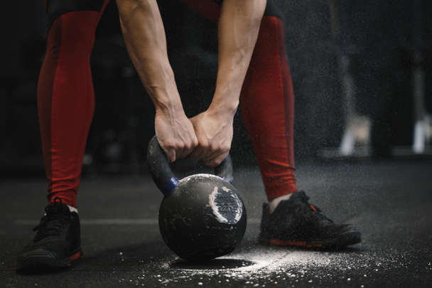 Closeup of crossfit woman lifting heavy kettlebell at gym. - Foto, Imagen