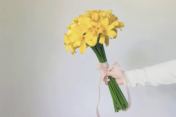 holding yellow lily flower bouquet in hand  - Valokuva, kuva