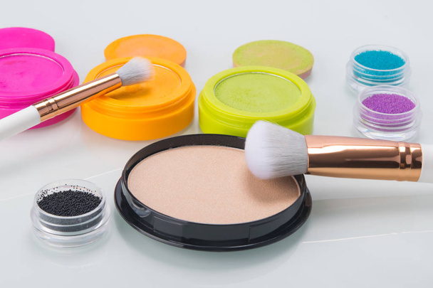 on a bright table, items for makeup, colorful shadows, powder and brushes for applying - Foto, Imagen