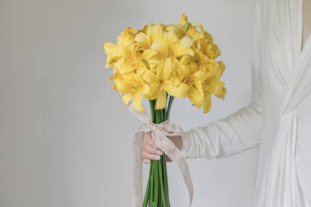 vestido branco mulher segurando amarelo lírio buquê de flores
  - Foto, Imagem