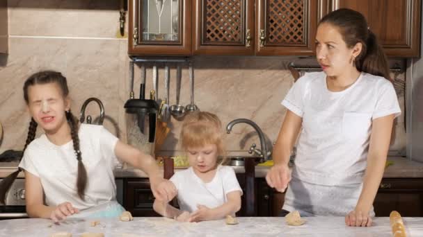 Mama i córki rzucają mąkę do siebie podczas gotowania w kuchni. - Materiał filmowy, wideo