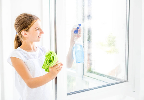 Chica adolescente ventana de limpieza con spray
 - Foto, imagen