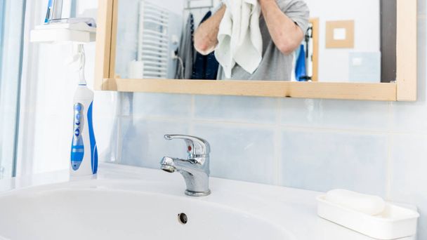 Bathroom sink and man in background - Фото, зображення