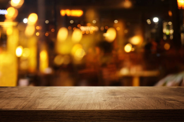 background of wooden table in front of abstract blurred restaurant lights - Photo, Image