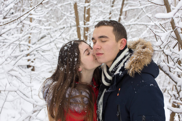 Il ragazzo e la ragazza si riposano nei boschi invernali. Marito e moglie nella neve. Giovane coppia a piedi nel parco invernale - Foto, immagini