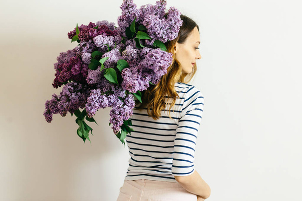 Attractive girl with a violet bouquet of lilac on a white background - Foto, afbeelding