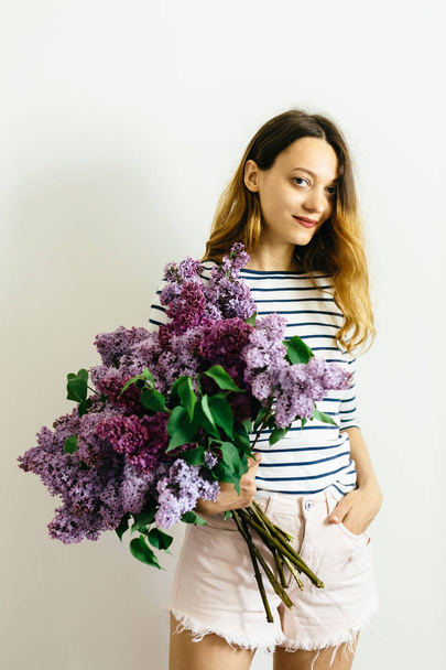 Attractive girl with a violet bouquet of lilac on a white background - Photo, Image