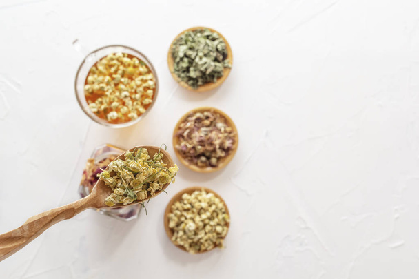 Травяной чай с фармацевтической ромашкой, сухой хризантемы и охотники на белом столе
. - Фото, изображение