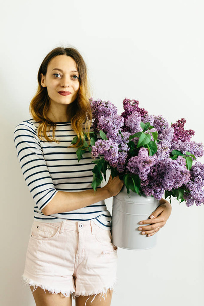 Attractive girl with a violet bouquet of lilac on a white background - Valokuva, kuva
