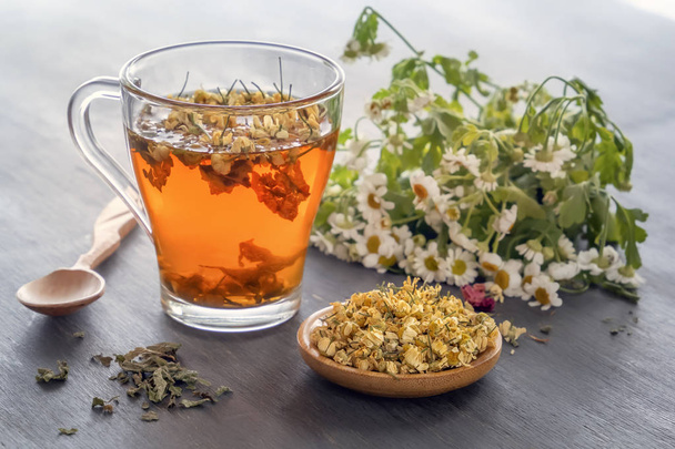 Chá de ervas com camomila farmacêutica em uma mesa de madeira cinza. Close-up
 - Foto, Imagem